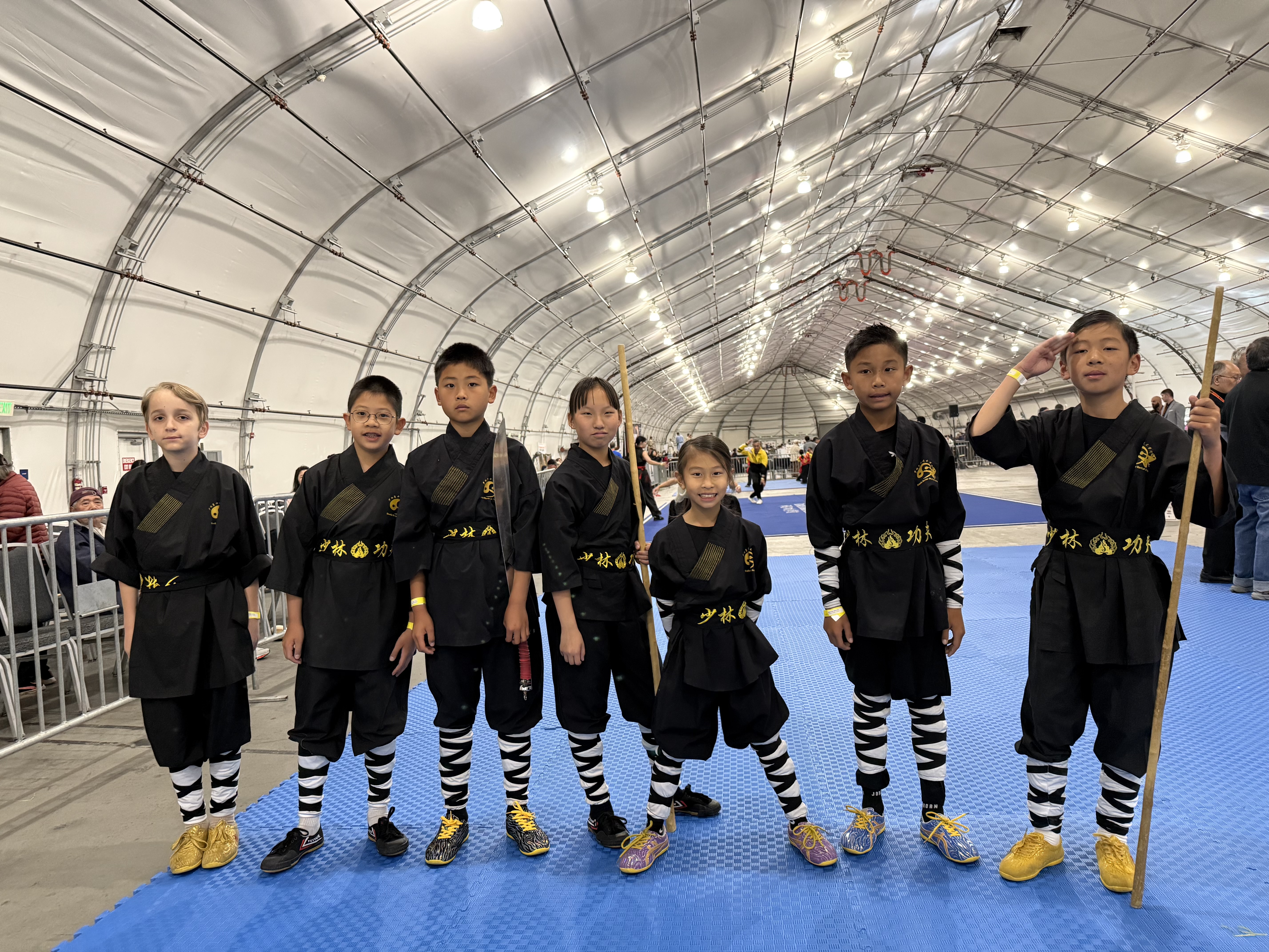 Students in black uniforms assembled with staffs before competition