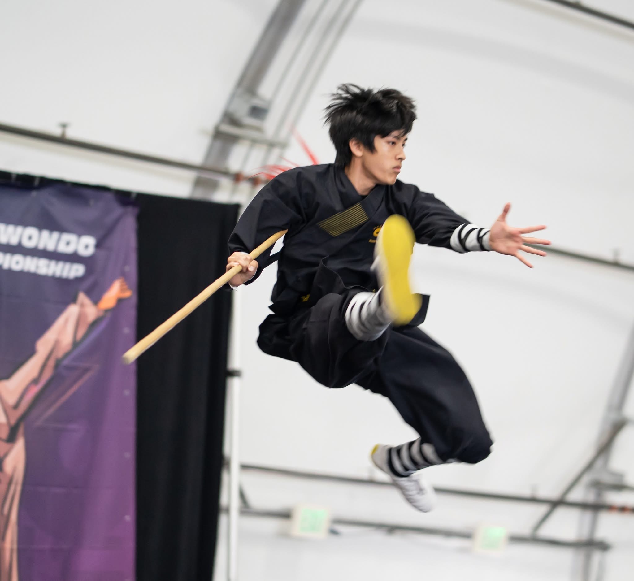 Student airborne with staff at competition
