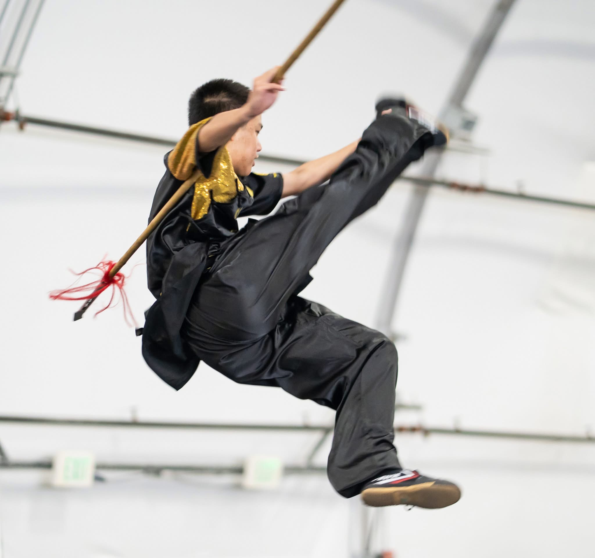 Student leaping with staff at competition
