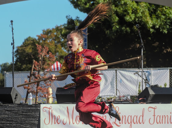 Student demonstrating traditional staff form at outdoor event